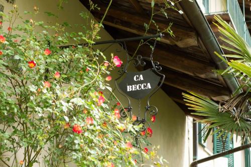 a sign hanging from the side of a building with flowers at Ca' Becca-Bioglio in Bioglio