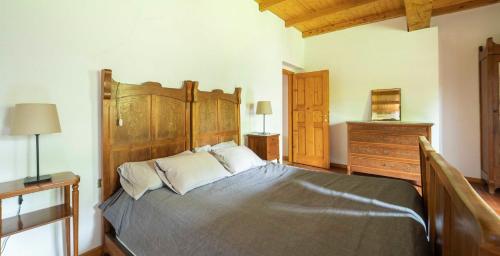 a bedroom with a large bed with a wooden headboard at Ca' Becca-Bioglio in Bioglio