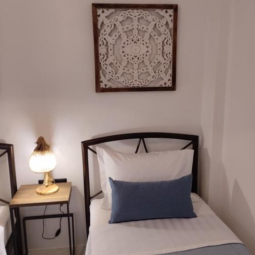a bed with a blue pillow and a picture on the wall at Thanos ,Rooms and Apartments in Ouranoupoli