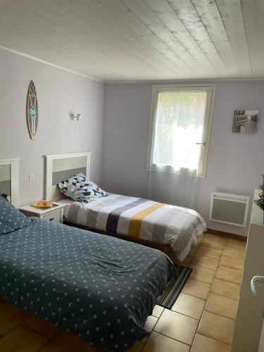 une chambre avec deux lits et une fenêtre dans l'établissement Grande maison familiale, à Lacanau
