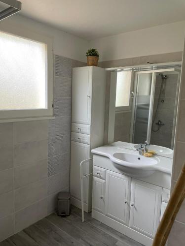 une salle de bain blanche avec un lavabo et un miroir dans l'établissement Grande maison familiale, à Lacanau
