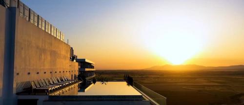 a view of a building with the sunset in the background at Grand Sapphire 107 Amazing 1 Bedroom Apartment By MyGuest Cyprus in Iskele