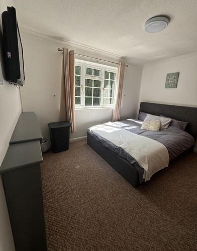 a bedroom with a bed and a flat screen tv at A Stunning 3 bed family Home - Woodcote House in Carshalton