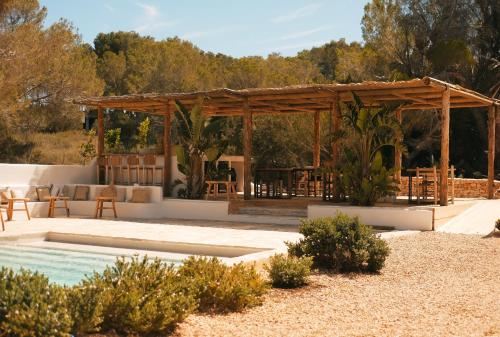 um pavilhão com uma mesa e cadeiras e uma piscina em Estel Formentera em Es Migjorn