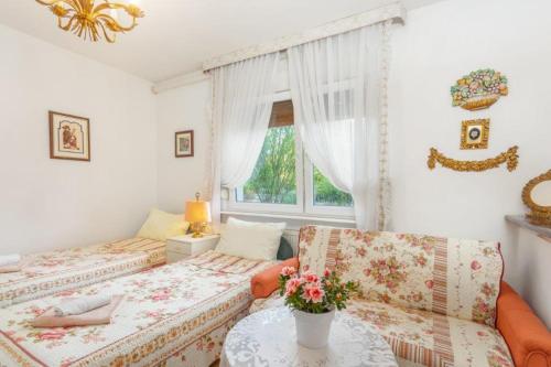 Zimmer mit 2 Betten und einem Tisch mit Blumen in der Unterkunft AUTOMOTODROM GROBNIK - Apartments and Rooms Skejić in Čavle