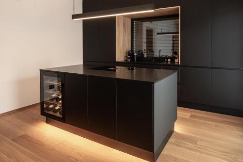 a kitchen with black cabinets and a black counter top at Luxury Penthouse - Between Kronplatz, 3 Peaks Dolomites and Lake Prags in Monguelfo