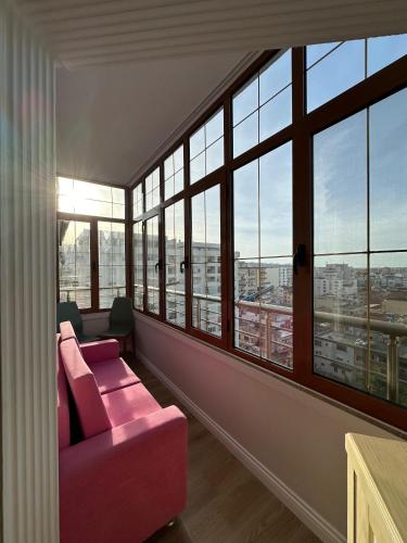 a living room with a pink couch and large windows at classy apartment Lea 3 in Durrës