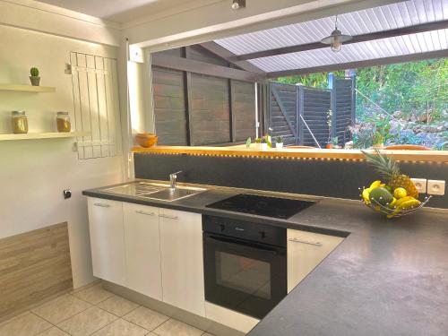 a kitchen with a sink and a stove top oven at Habitation Bellevue in Sainte-Anne