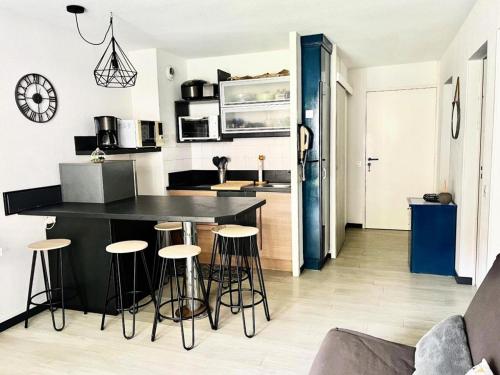 une cuisine avec un comptoir noir et des tabourets de bar dans l'établissement Résidence Le Boucanier - 2 Pièces pour 6 Personnes 694, à Vieux-Boucau-les-Bains