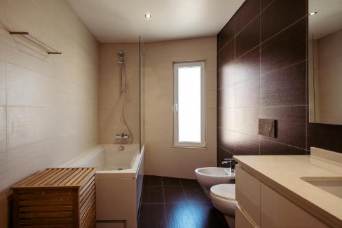 een badkamer met een bad, een toilet en een wastafel bij Casa do Peixinho in Ericeira