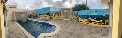 una camera con un dipinto sul muro e una piscina di Dar lamisse Djerba a Houmt Souk