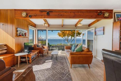 a living room with leather furniture and a view of the ocean at Henley - Omori Holiday Home in Kuratau