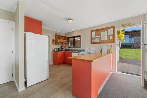 a kitchen with red cabinets and a white refrigerator at Henley - Omori Holiday Home in Kuratau