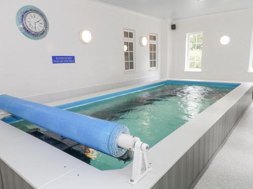 a large swimming pool in a room with a clock at Rosehill Manor in Market Drayton