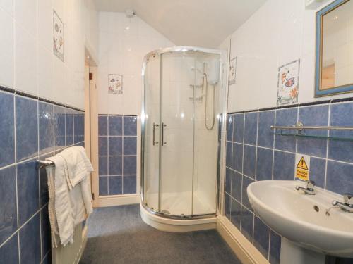a blue tiled bathroom with a shower and a sink at Rosehill Manor in Market Drayton