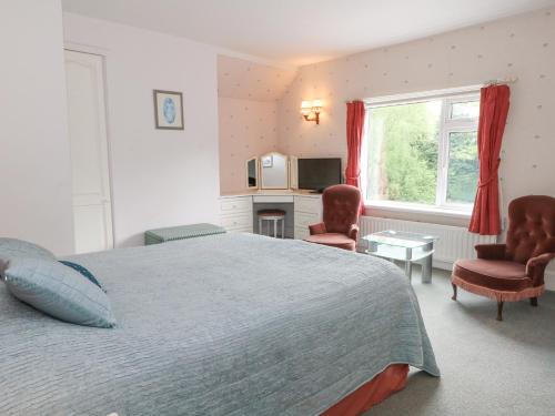 a bedroom with a bed and two chairs and a window at Rosehill Manor in Market Drayton