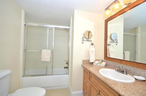 uma casa de banho com um lavatório e um chuveiro com um espelho. em Fort Lauderdale Beach Resort by Vacatia em Fort Lauderdale