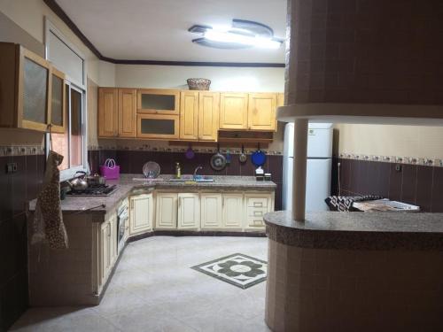 a kitchen with wooden cabinets and a white refrigerator at Villa haydi in Oujda