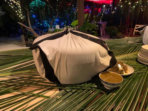 an umbrella on a table with a plate of food at Turtle Maldives - Your Gateway to the Beach & Marine Adventures Await! in Omadhoo