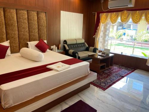 a bedroom with a bed and a chair and a window at Saikat Saranya Resort, Mandarmoni Beach in Mandarmoni