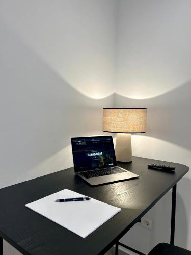 a laptop computer sitting on a desk with a pen and paper at Pensión La Orozca Benidorm in Benidorm