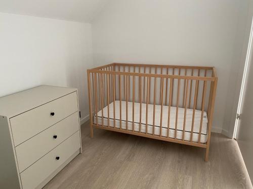 ein Kinderbett und eine Kommode in einem Zimmer in der Unterkunft Paradis på Sørlandet 2 in Kristiansand