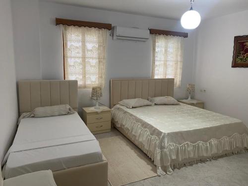 1 dormitorio con 2 camas y 2 ventanas en N'Eden Hostel en Berat
