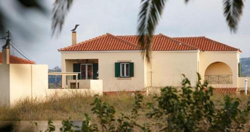 a white house with a red roof and a green window at Kostantina's House Kythera in Kámbos