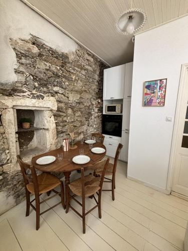 une salle à manger avec une table et un mur en pierre dans l'établissement Gustave charmant appartement en cœur de ville à 20 mètres de la mer, à Les Sables-dʼOlonne