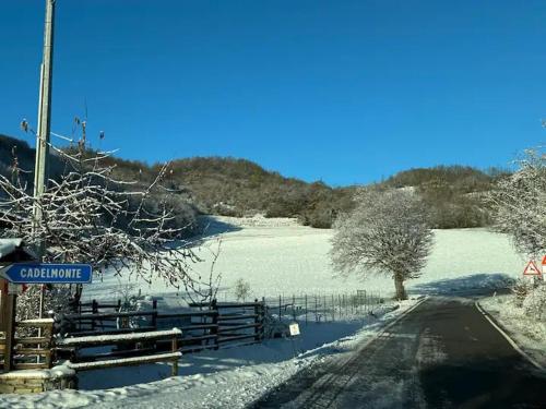 a snow covered field with a fence and a road at Casa del Giglio a Cadelmonte in Valle