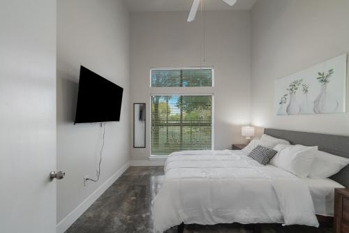 um quarto branco com uma cama e uma televisão de ecrã plano em Uptown 1br Apartment, Pool, Gym, Parking Cs em Dallas