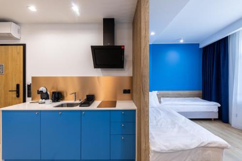 una cocina con armarios azules y una cama en una habitación en SQUARE APARTMENTS GDYNIA, en Gdynia