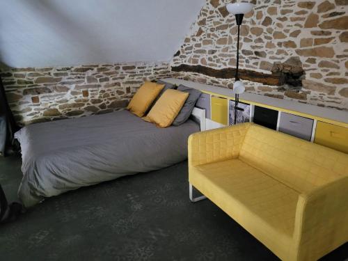 a bedroom with a bed and a yellow couch at Tout au bout du chemin in Réquista