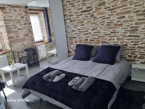 a bedroom with a bed with two pairs of slippers on it at Tout au bout du chemin in Réquista
