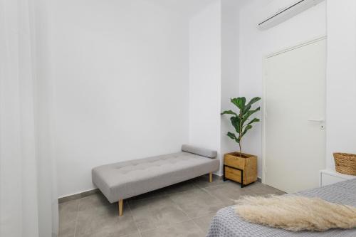 a white room with a bench and a potted plant at Alpha & Omega Apartments in Karpathos Town