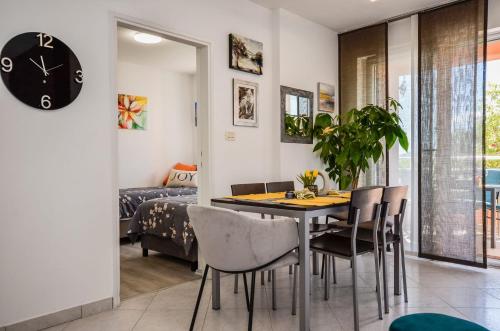 Un comedor con una mesa y sillas y un reloj. en Apartman Kiki, en Rabac