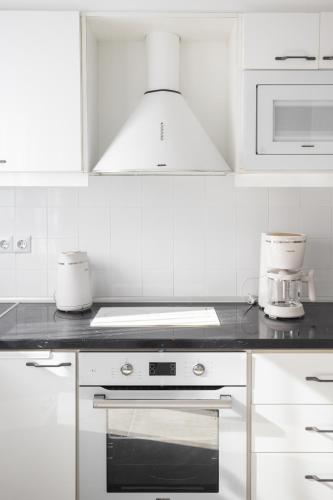 a kitchen with white cabinets and a stove top oven at Alpha & Omega Apartments in Karpathos Town