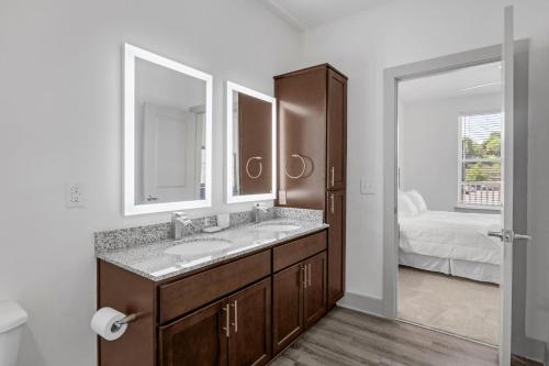 a bathroom with a sink and a mirror and a bed at Modern Luxury In The Heart Of Knoxville in Knoxville