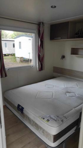 un grand lit dans une chambre avec une fenêtre dans l'établissement Mobil home confort - Plage Piscine - 4 personnes - La Cotinière - Ile d'Oléron, à La Cotinière