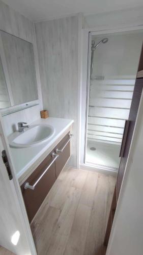 une salle de bain blanche avec un lavabo et une douche dans l'établissement Mobil home confort - Plage Piscine - 4 personnes - La Cotinière - Ile d'Oléron, à La Cotinière