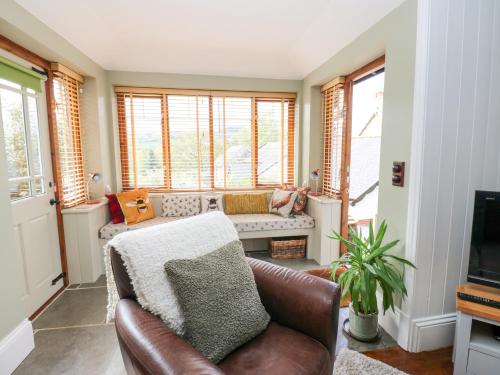 a living room with a leather couch and windows at Bee Garth in Castleton