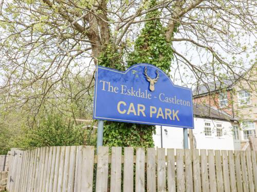 a blue sign for a car park in front of a fence at Bee Garth in Castleton