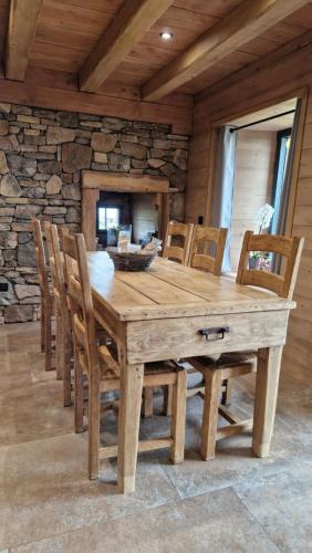 a wooden table and chairs in a room with a stone wall at La ferme de Jouane in Besse-et-Saint-Anastaise