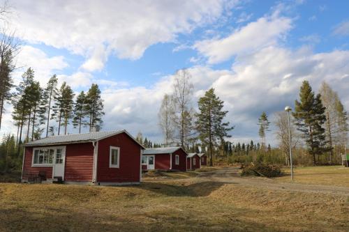 a couple of small red buildings in a field at Trehörningsjö camping & stugor in Norrfors