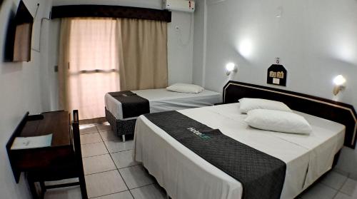 een slaapkamer met 2 bedden, een stoel en een raam bij Hotel LF By Feliciano in Barracão