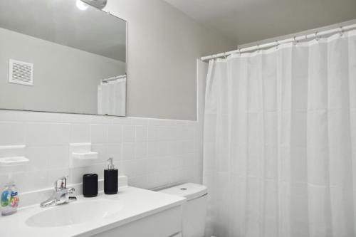 威爾明頓的住宿－Stunning Retreat In Wilmington I Free Parking!，白色的浴室设有淋浴帘和水槽