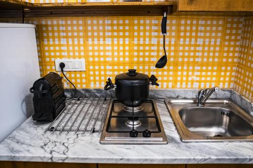 a pot sitting on top of a stove next to a sink at Davids Room Palazzo Tamborino in Lecce