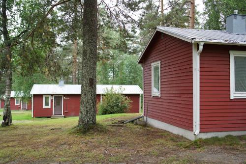 a red house with a tree in front of it at Trehörningsjö camping & stugor in Norrfors