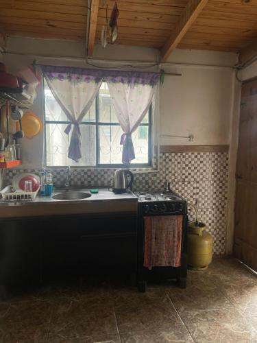 cocina con fogones, fregadero y ventana en Tres Lunas Alojamiento Doble, en Chuy