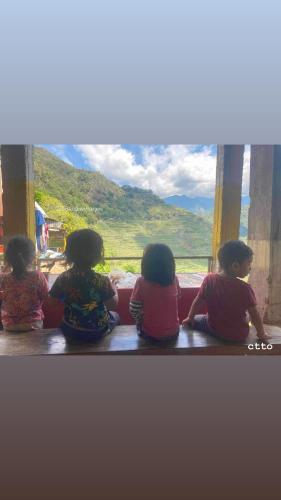 three children sitting on the floor looking out of a window at Batad Pension PH in Banaue